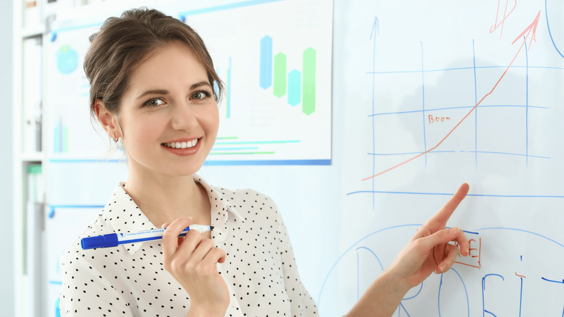 Mulher sorridente com camisa branca de bolinhas pretas aponta para um gráfico de linha crescente e a palavra