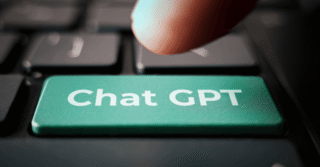 Dedo apertando tecla com de um teclado com o botão verde escrito Chat GPT.